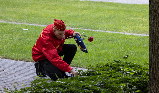 رجل يضع علمًا وزهورًا على صورة أحد أفراد أسرته خلال احتفال في ذكرى