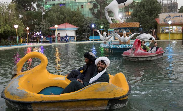 رجال أفغان يركبون قوارب في حديقة في هرات