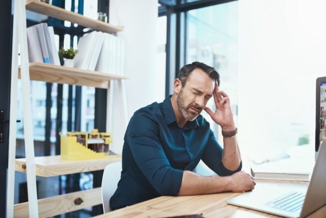 male-head-pan-ache-work-stress-laptop-desk