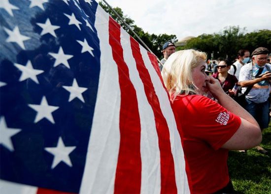 ديان من نيويورك من مجموعة انظر إلى الأمام أمريكا تمسح عينيها وهي تحمل العلم الأمريكي أثناء احتجاجها