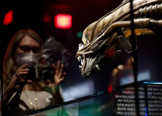 ضيفة تستخدم هاتفها بواسطة غطاء رأس مخلوق من فيلم Alien