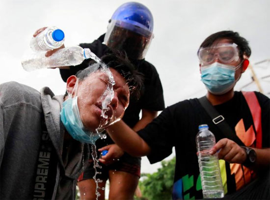 يصب المتظاهرون الماء على وجه زميلهم أثناء مساعدته له خلال احتجاج على تعامل الحكومة التايلاندية مع جائحة فيروس كورونا ومطالبة رئيس الوزراء برايوت تشان أوتشا باستقالة
