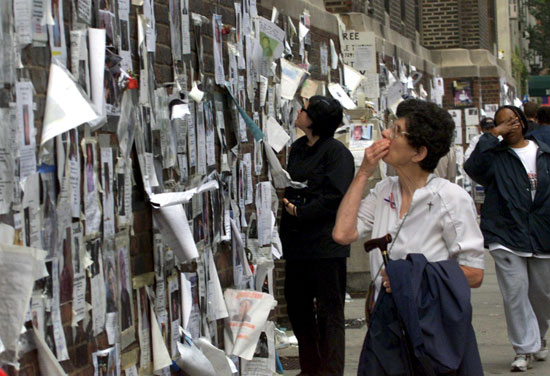 امرأة تنظر إلى الصور والرسائل التي تبحث عن الأشخاص المفقودين على جدار في مانهاتن