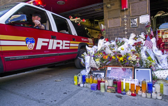 نصب تذكاري للزهور والشموع والعلم الأمريكي شوهد خارج محطة إطفاء في نيويورك