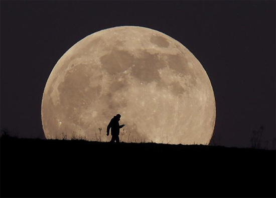رجل يسير فوق إيفينغو بيكون بينما يرتفع القمر الذئب