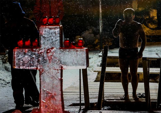 رجل يضع علامة صليب قبل الغطس في المياه الجليدية خلال الاحتفالات بعيد الغطاس للمسيحيين