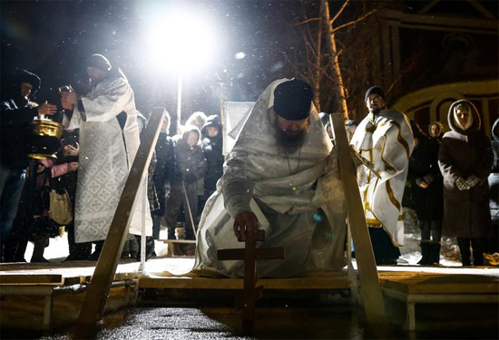 كاهن يبارك الماء خلال احتفالات المسيحيين الأرثوذكس بعيد الغطاس في روسيا