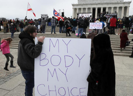 أشخاص يحملون لافتة خارج نصب لنكولن التذكاري خلال مسيرة معارضة لتفويضات كوفيد