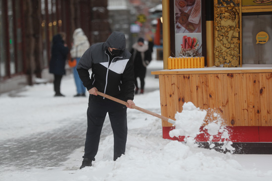رجل ينظف شارعًا أثناء تساقط الثلوج