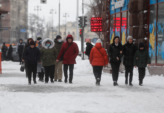 الناس يسيرون في شارع أثناء تساقط الثلوج