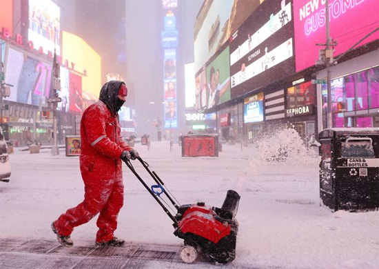 عامل يزيل الثلج في تايمز سكوير خلال عاصفة نورستر في مانهاتن