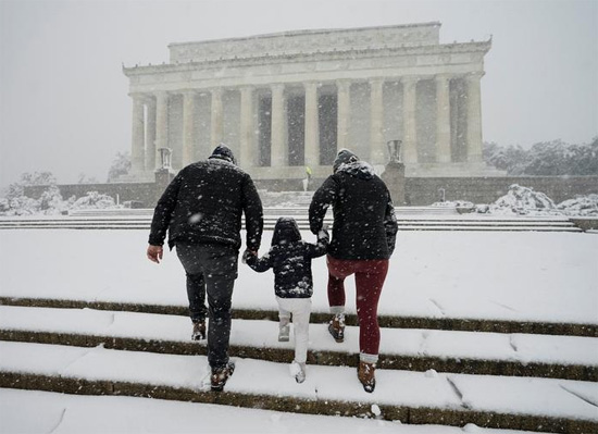زوجان يمشيان مع طفلهما على درجات سلم نصب لنكولن التذكاري