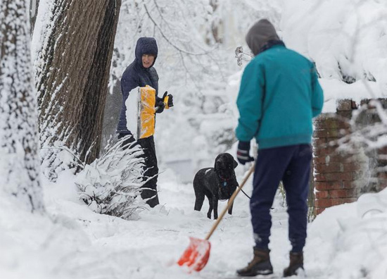 السكان المحليون يزيلون الثلوج أمام منازلهم