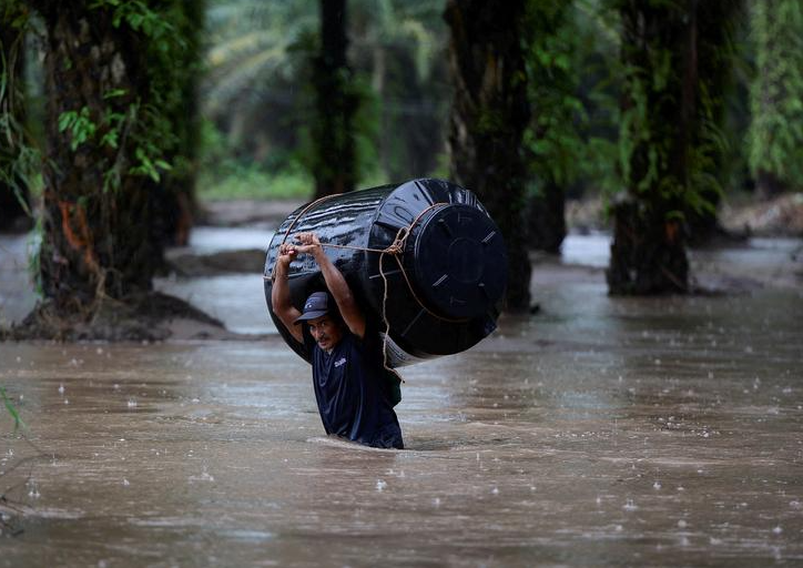 رجل يحمل خزان مياه فارغًا عبر منطقة غمرتها المياه بعد تأثير العاصفة الاستوائية جوليا في بروغريسو بهندوراس في 9 أكتوبر  تشرين الأول. رويترز  يوسف أمايا