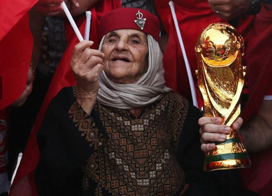 مشجع تونسي يقف مع نسخة طبق الأصل من كأس العالم