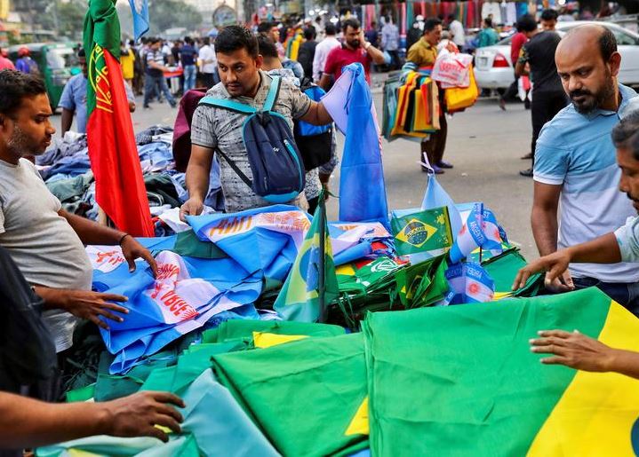 المشجعون يتجمعون في متجر في الشارع لشراء أعلام فريقهم المطلوب قبل كأس العالم لكرة القدم ، في دكا ، بنغلاديش