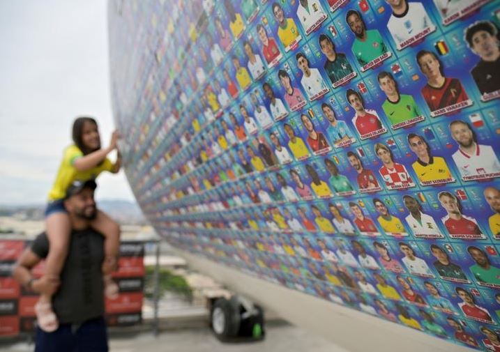 فتاة تلصق ملصقات كأس العالم لكرة القدم على طائرة معروضة خلال حدث لكأس العالم لكرة القدم 2022 في بيلو هوريزونتي بالبرازيل