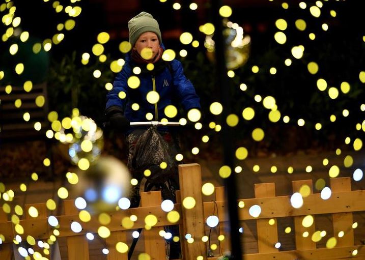 طفل يركب دراجة لتشغيل تركيبات أضواء عيد الميلاد في ساحة مقاطعة بودابست لتوفير التكاليف باستخدام الأضواء المستدامة