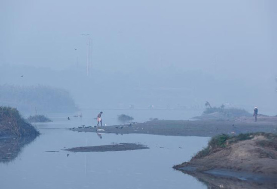 رجل يسير وسط الضباب الدخاني الكثيف بعد الاستحمام في نهر يامونا في نيودلهي