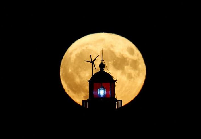 اكتمال القمر المعروف باسم باك مون خلف منارة في سان نازير ، فرنسا