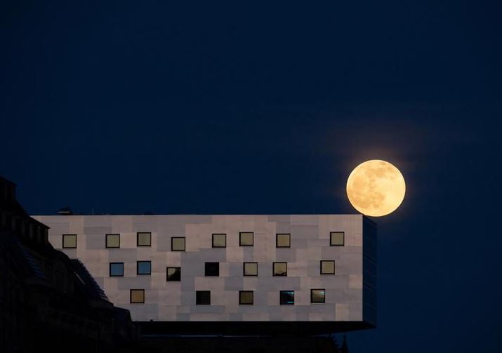 البدر ، المعروف باسم القمر الوردي يرتفع خلف فندق في برلين ، ألمانيا