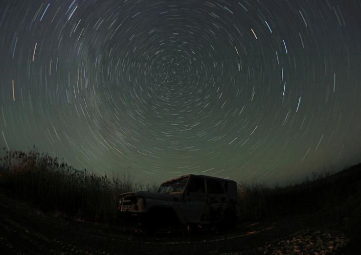 صورة تعرض طويلة تظهر نجومًا فوق سيارة مهجورة على ضفة نهر إيلي في منطقة ألماتي ، كازاخستان