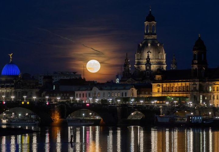 القمر المكتمل المعروف باسم قمر الفراولة يرتفع خلف منطقة البلدة القديمة ، في دريسدن ، ألمانيا