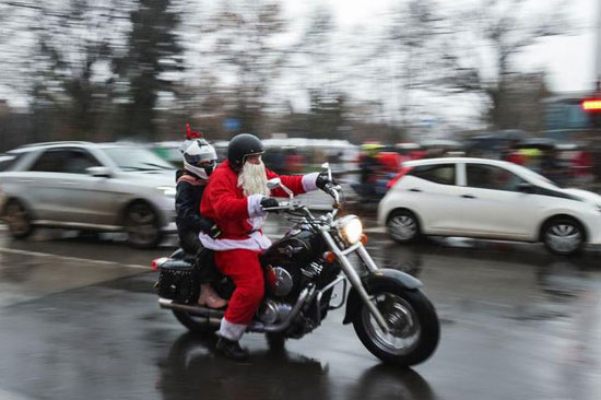 أشخاص يرتدون بدلات بابا نويل يركبون دراجاتهم النارية خلال سباق سانتا رايد السنوي