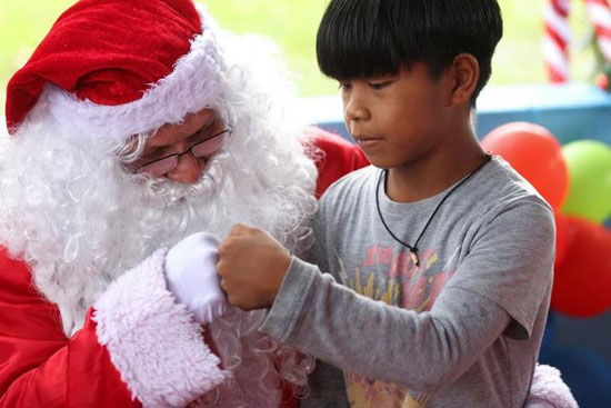 رجل  يرتدي زي بابا نويل يرفع قبضة يده لطفل فى البرازيل
