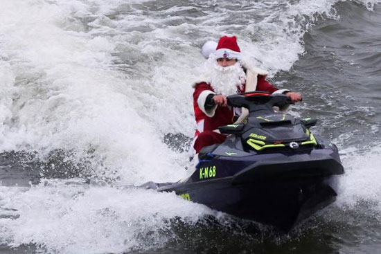 رجل يرتدي زي بابا نويل يركب زلاجة مائية على نهر الراين في كولون بألمانيا