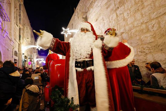 فلسطيني يرتدي زي بابا نويل ويشير خلال احتفال في بيت لحم بالضفة الغربية