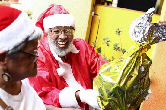 ميلتون باربوسا  مؤسس الحركة السوداء الموحدة  يرتدي زي بابا نويل ويحمل هدية خلال توزيع للأطفال