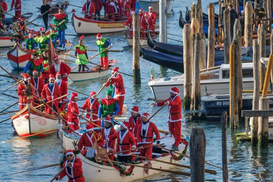 أشخاص يرتدون زي بابا نويل خلال سباق القوارب في عيد الميلاد