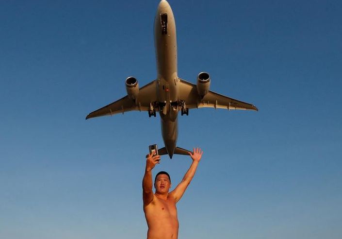 إيفان ، سائح من روسيا ، يلتقط صورة سيلفي على شاطئ ماي خاو بينما تقلع طائرة من مطار بوكيت الدولي في بوكيت بتايلاند