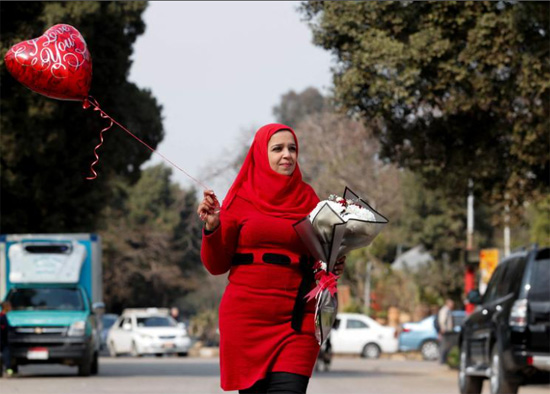 امرأة تحمل وردة وبالونًا أثناء الاحتفال بعيد الحب في القاهرة