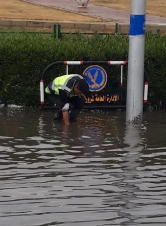 أحد رجال الشرطة يساعد في سحب مياه الأمطار
