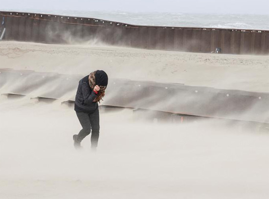 شخص يسير بينما تتكسر الأمواج على الشاطئ في أعقاب العاصفة يونيس في بلانكنبرج  بلجيكا