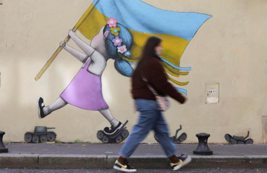 امرأة تمر أمام لوحة جدارية لدعم أوكرانيا لفنان الشارع الفرنسي