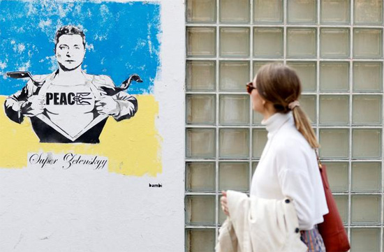 مرأة تمشي أمام عمل فني يصور الرئيس الأوكراني فولوديمير زيلينسكي للفنان بامبي في لندن