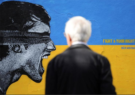 رجل ينظر إلى لوحة جدارية دعما لأوكرانيا رسمها فنان الشارع الفرنسي