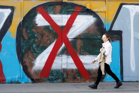 امرأة تمشي أمام عمل فني دعما لأوكرانيا في لندن