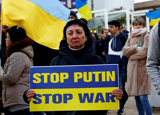 امرأة تتفاعل وهي تحمل لافتة احتجاج في مظاهرة لدعم أوكرانيا
