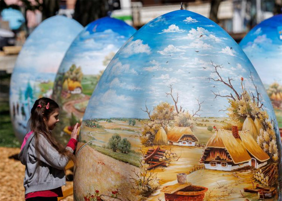 فتاة تنظر إلى بيض عيد الفصح الذي يبلغ ارتفاعه مترين والمرسوم  في كوبريفنيكا  كرواتيا
