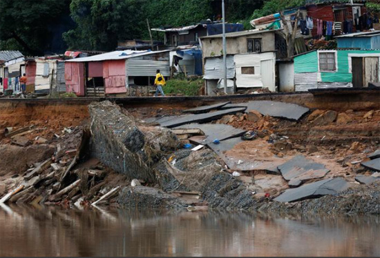 رجل يسير على طريق مدمر بعد الفيضانات