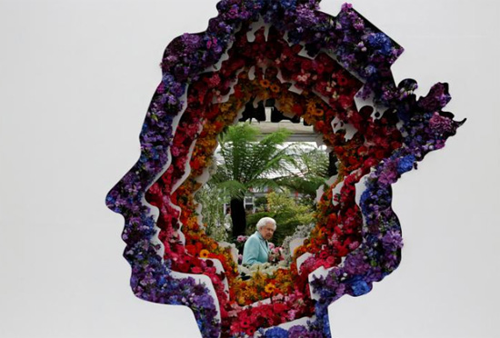 تم التقاط صورة للملكة إليزابيث الثانية من خلال فجوة في معرض للزهور في سوق نيو كوفنت جاردن للزهور