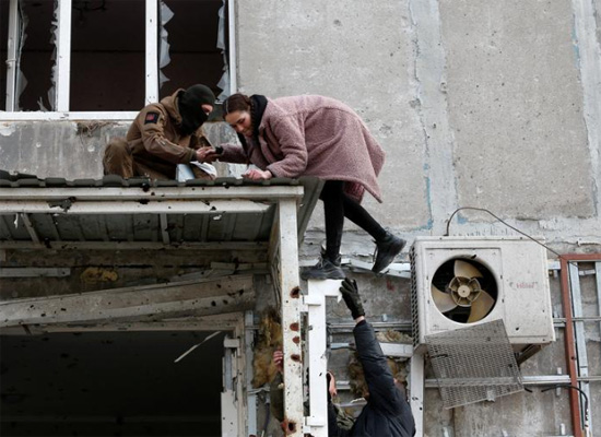 أشخاص يأخذون متعلقاتهم من مبنى سكني دمر خلال الصراع الأوكراني الروسي