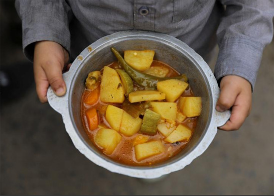 صبي يحمل وجبة حصل عليها من مطبخ خيري في صنعاء اليمن