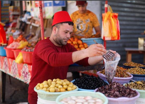 بائع فلسطيني يبيع الزيتون والمخللات في سوق خلال شهر رمضان المبارك