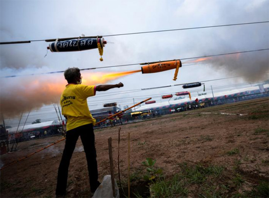 رجل يقف بجانب صاروخ خلال مهرجان تقليدي للصواريخ  في مقاطعة باثوم ثاني بتايلاند