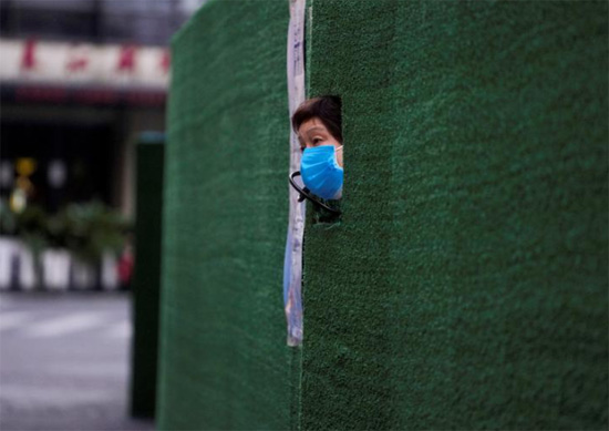 أحد السكان ينظر من فجوة في الحاجز في منطقة سكنية أثناء الإغلاق في شنجهاي الصين